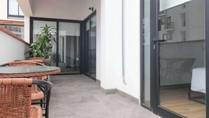 Un intérieur moderne avec une porte vitrée donnant sur un balcon, des meubles en osier et une plante en pot.