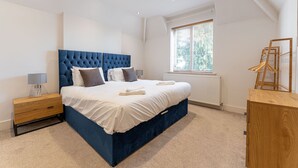 A bedroom with a large bed, a wooden nightstand, a dresser, and a window with blinds. - Large Home near Edgbaston Stadium, UOB & QE hospital sleeps 6 (Birmingham)