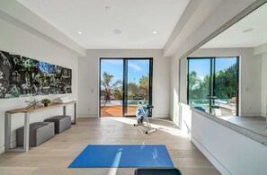 Enjoy a serene view of the outdoor pool and lush greenery from the comfort of your room, which offers a stationary exercise bike and space for relaxation.