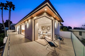 A modern house with a spacious patio, a dining area, and a living room with contemporary furniture.