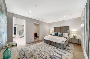 Relax in this serene bedroom with a large bed, bedside table, and comfortable seating area.