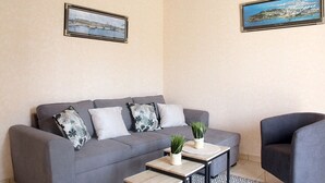 A living room with a grey sofa, two armchairs, a coffee table, and two framed pictures on the walls. - L'Armoricaine (Cancale)