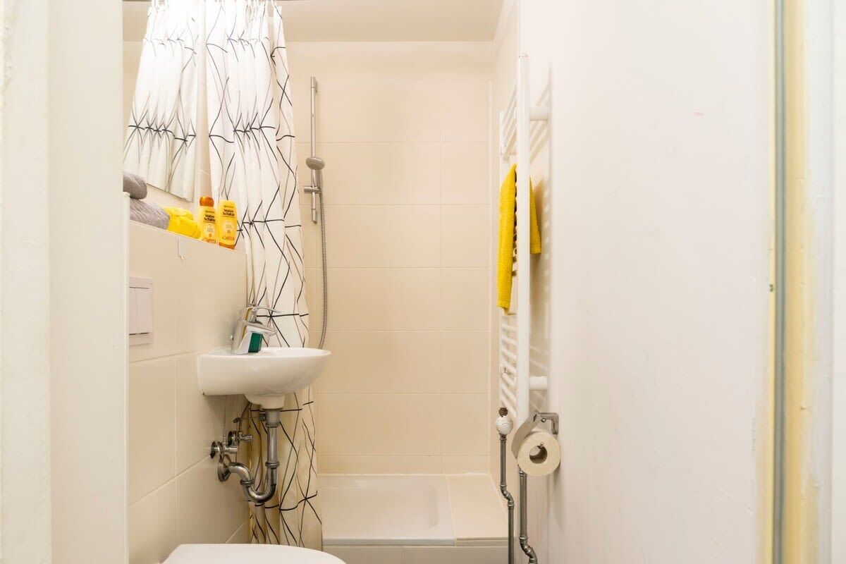 A bathroom with a toilet, sink, shower, and a towel rack.