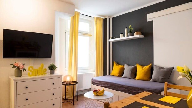 A modern living room with a sofa, TV, and a small table with a bowl of fruit. - 2-Bedroom-Apartment in Berlin-Kreuzberg (Berlin)