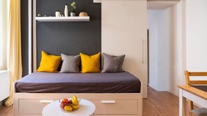 A modern bedroom with a bed, bedside table, and a small white table with fruit. - 2-Bedroom-Apartment in Berlin-Kreuzberg (Berlin)