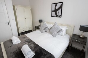 A hotel room with a bed, a wardrobe, a nightstand, and a framed picture on the wall. - Bright and Modern 1 Bed Bolton Apartment w WiFi (Bolton)