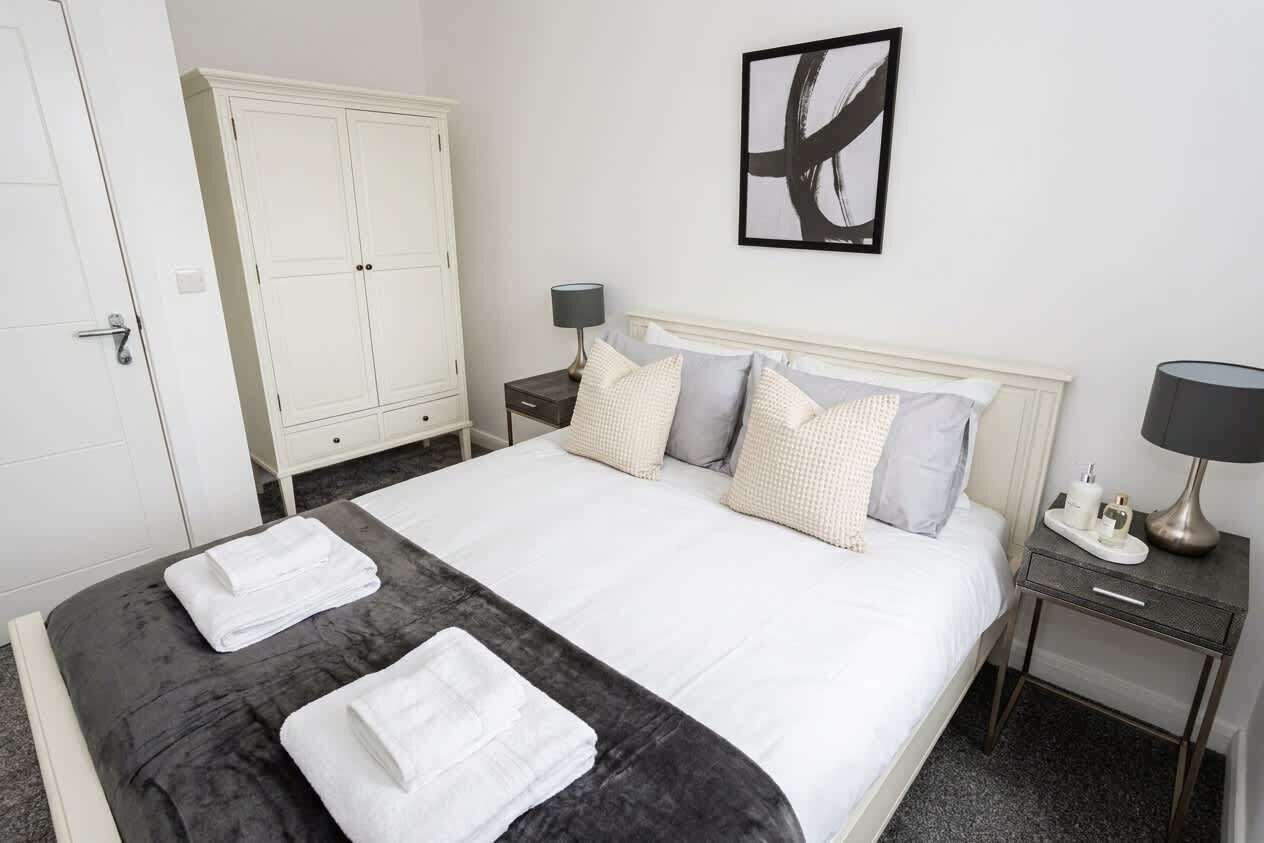 Une chambre d’hôtel comprenant un lit, une armoire, une table de chevet et une œuvre d’art accrochée au mur.