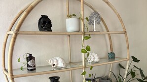 Una estantería redonda de bambú con varios objetos decorativos y plantas.