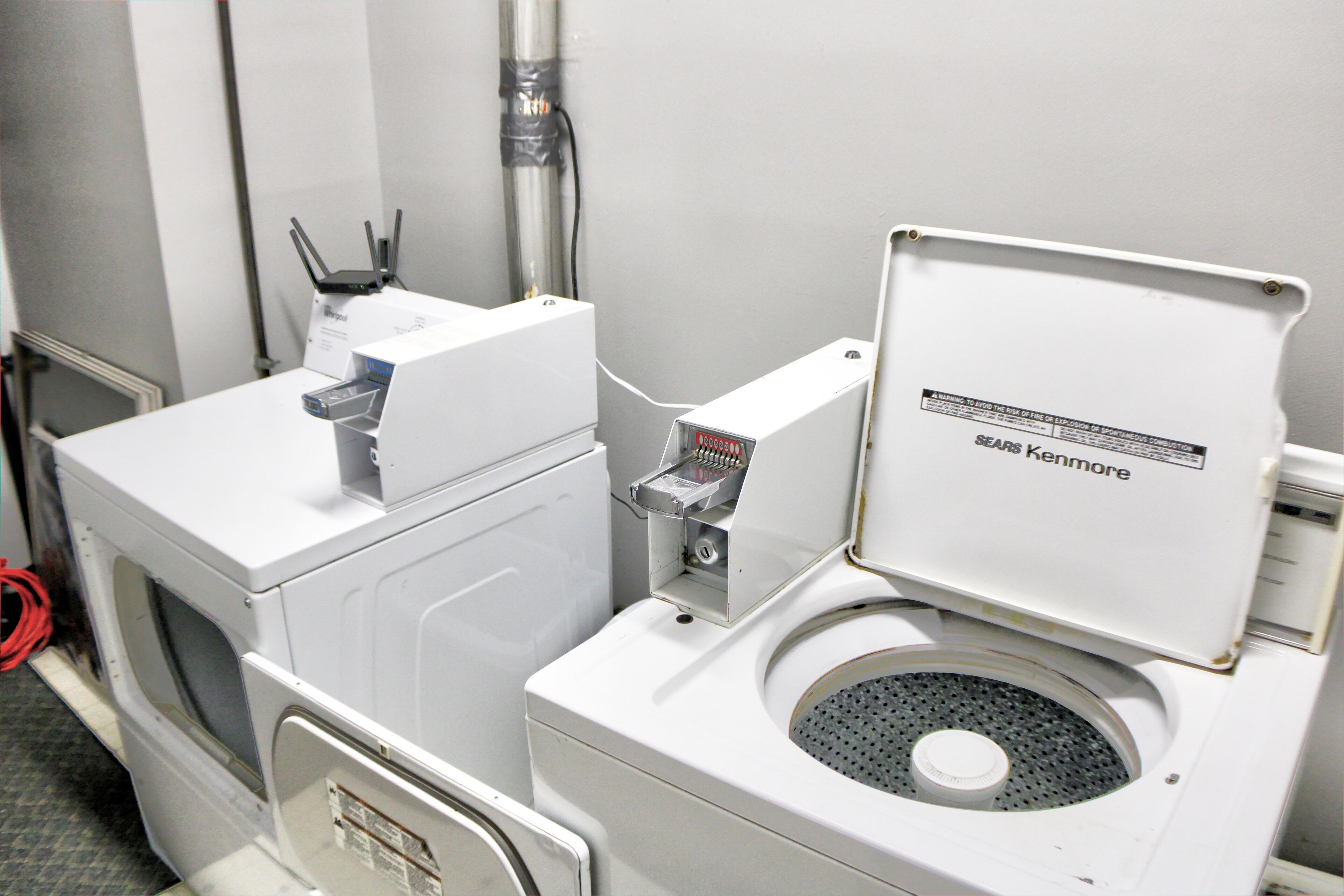 Un bagno compatto in stile industriale, con lavatrice e asciugatrice integrate, lavandino e WC.