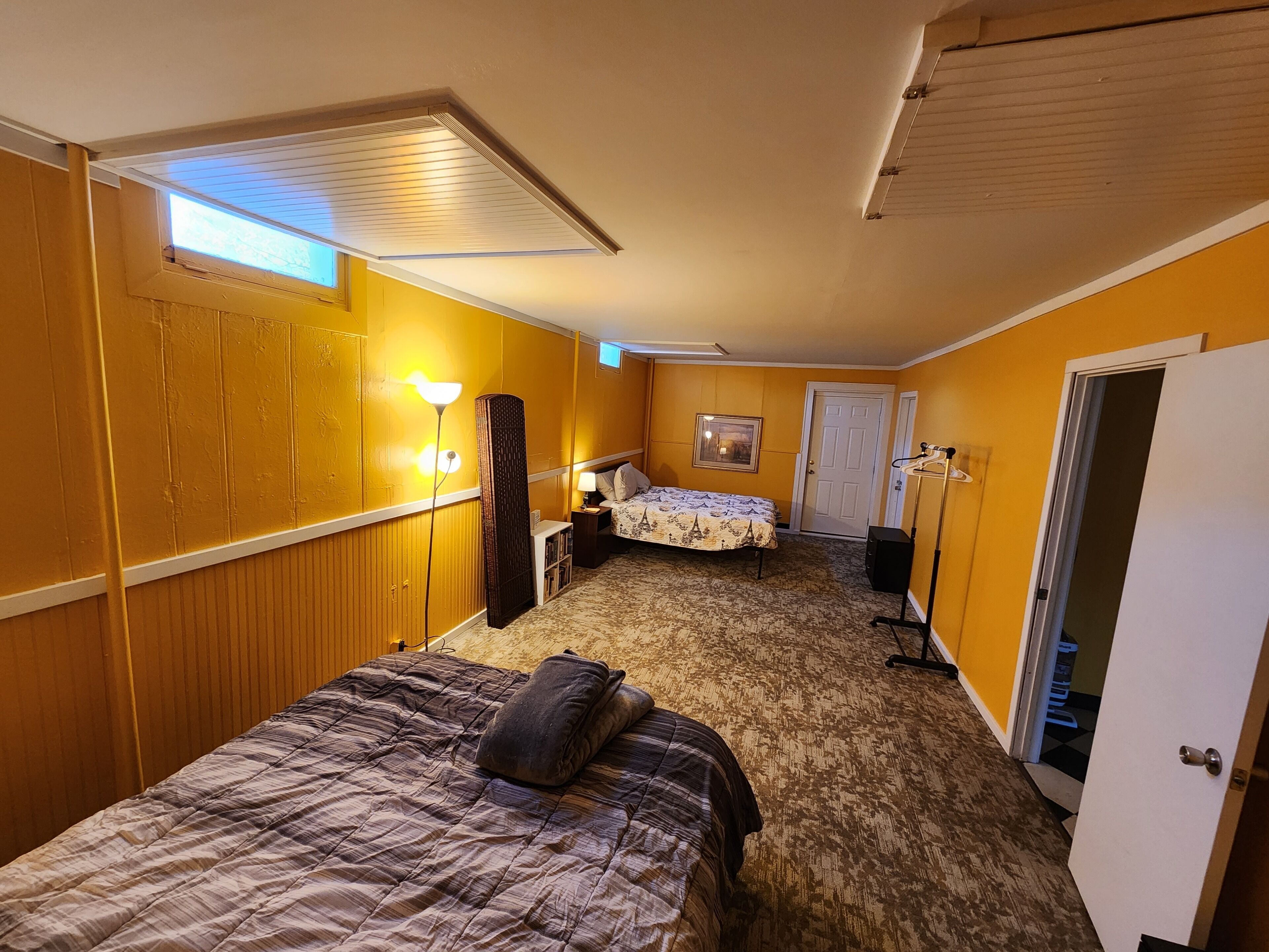 Habitación de hotel pequeña con dos camas, mesitas de noche, un armario, una puerta y una ventana.