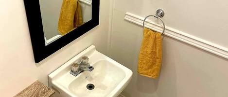 A bathroom with a white sink, a mirror, and a towel rack.