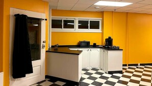 A kitchen with yellow walls, a black and white checkered floor, a ceiling fan, and a window above the sink.