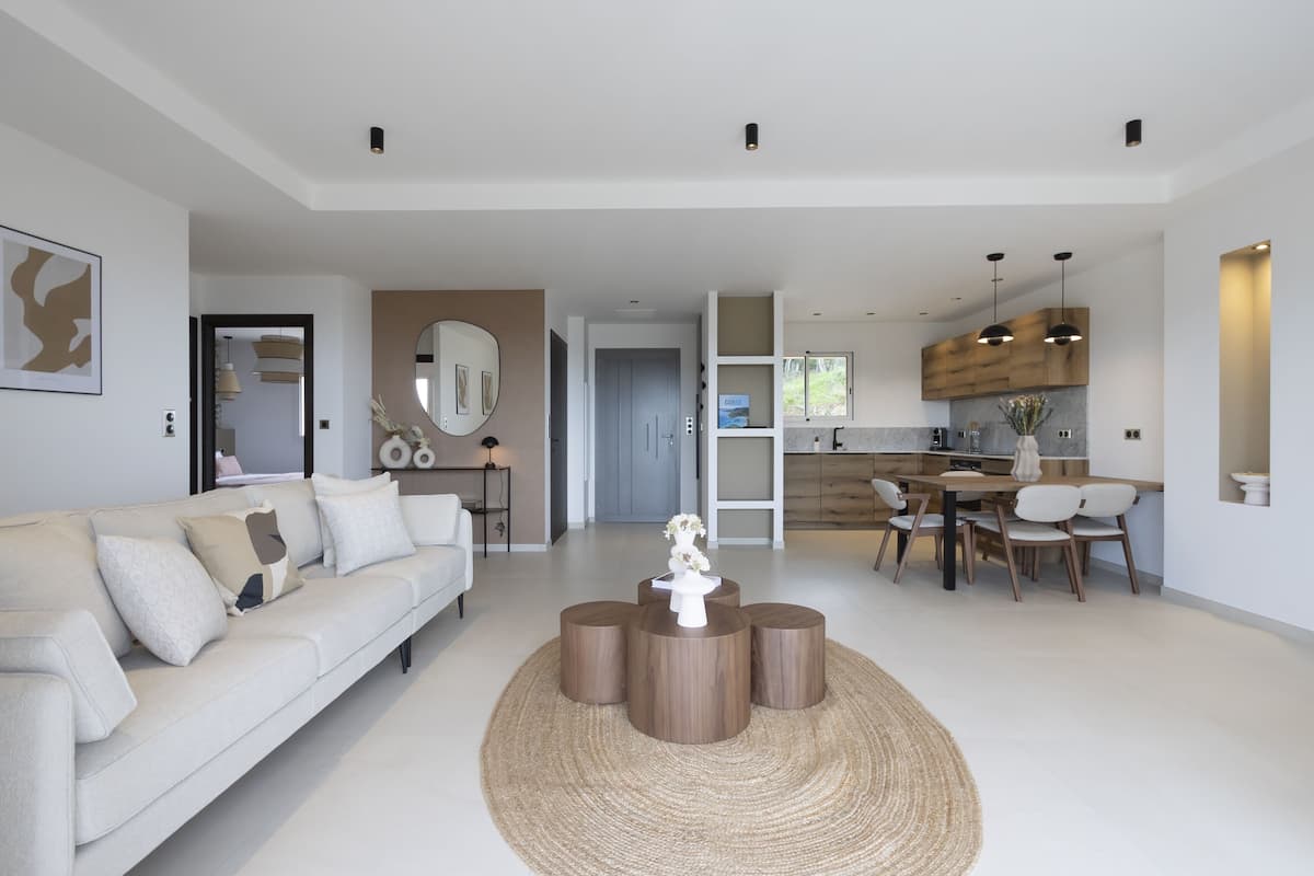 A modern living room with a sofa, coffee table, and dining area with chairs.
