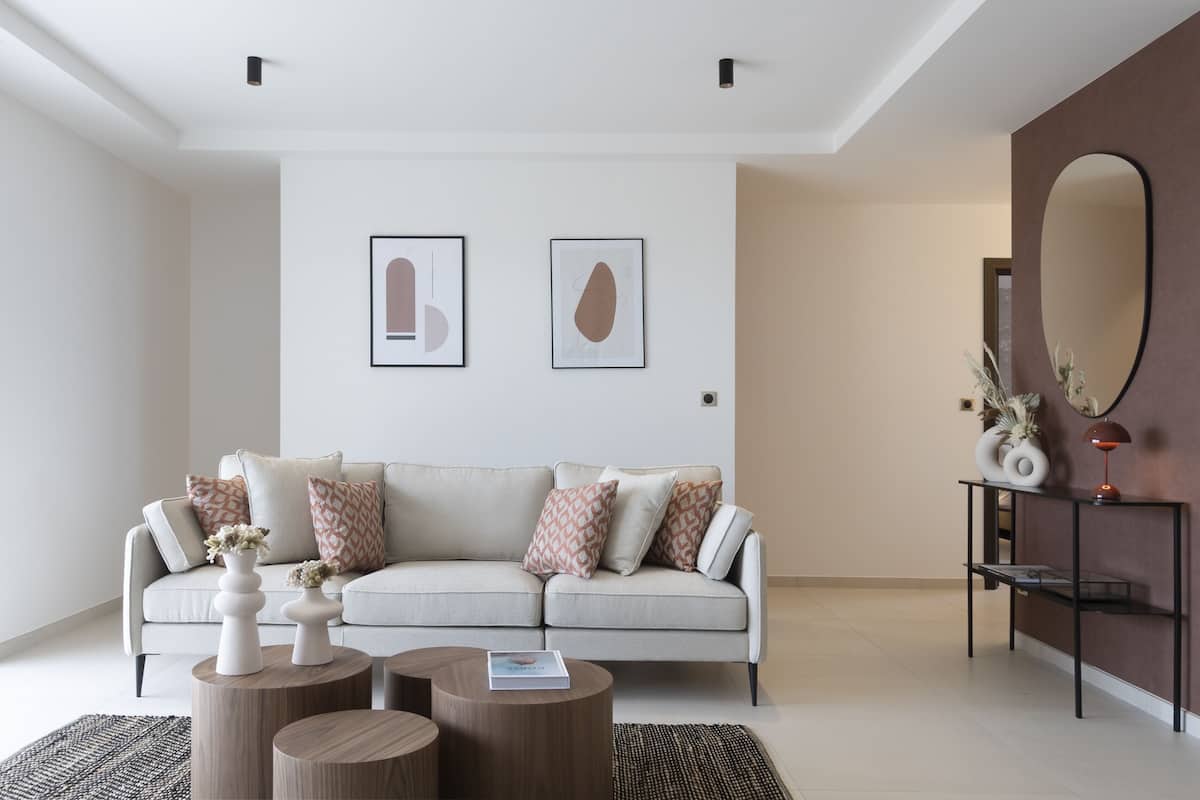 A modern living room with a sofa, coffee tables, and wall art.