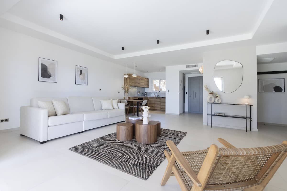 A spacious living area with a white sofa, a coffee table, and a wicker chair.