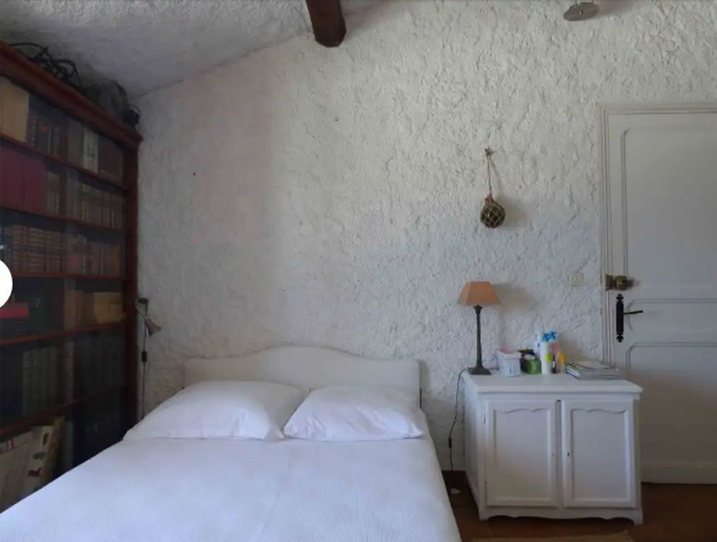 Une chambre à coucher avec un lit, une table de chevet, une lampe, une porte et une bibliothèque.