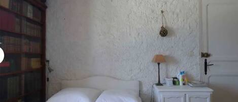 Une chambre à coucher avec un lit, une table de chevet, une lampe, une porte et une bibliothèque.
