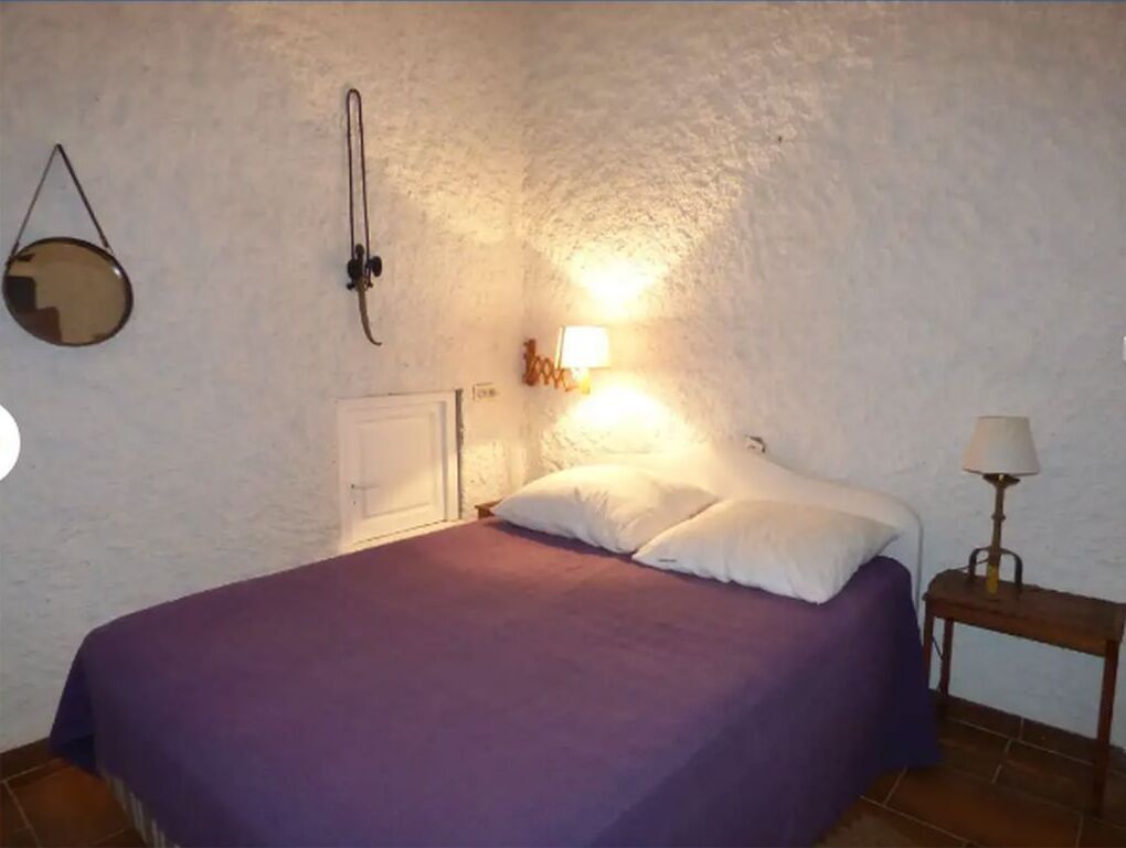 Une chambre à coucher comprenant un lit, une table de chevet, une lampe et un radiateur fixé au mur.