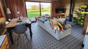 A cozy cabin interior with a wooden ceiling, a sofa, a dining table, and a TV. - Down the Rabbit Hole (Bristol)