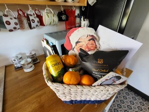 Una cesta con una botella de sidra, naranjas y una bolsa de patatas fritas West Country cheddar y cebolla.