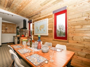 A wooden-paneled room with a dining table set for four, a kitchen area, and a world map on the wall.