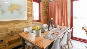 A wooden-paneled room with a dining table set for four, a world map on the wall, and a window with curtains. - Down the Rabbit Hole (Bristol)