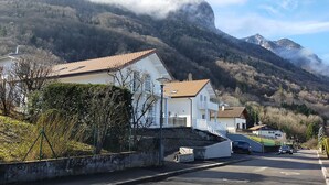 Una calle residencial con casas, un camino pavimentado y montañas al fondo.