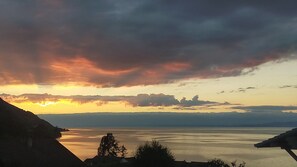 A sunset over a calm lake with distant mountains and a clear sky.