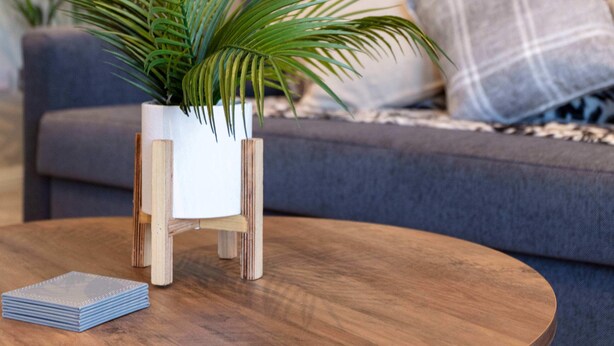 A round wooden table with a small potted plant and a stack of coasters. - London Gate No1 - Donnini Apartments (Kilmarnock)