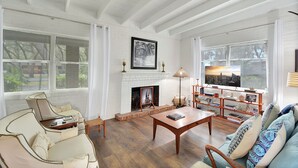 A spacious living room with a fireplace, a sofa, a coffee table, and a bookshelf.
