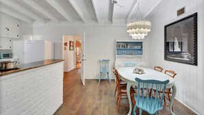 A dining area with a white brick wall, wooden floor, and a white table with blue chairs.