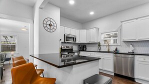 A modern kitchen with white cabinets, stainless steel appliances, and a black countertop. - Midtown Getaway (Kansas City)
