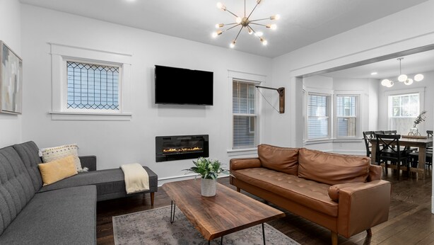 A modern living room with a grey sofa, a brown leather couch, a wooden coffee table, and a fireplace. - Midtown Getaway (Kansas City)