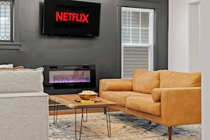 Un salón con sofá, una mesa de centro y un televisor de pantalla plana mostrando el logotipo de Netflix.