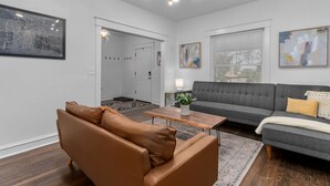 A modern living room with a brown leather sofa, a grey sofa, and a wooden coffee table. - Midtown Getaway (Kansas City)