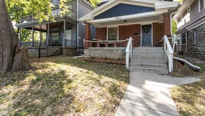 A two-story house with a front porch, a stone foundation, and a brick exterior. - Midtown Getaway (Kansas City)