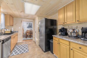 A modern kitchen with wooden cabinets, a stainless steel refrigerator, and a coffee station. - Riverside Cabin w/Fishing, Hot Tub & Firepit (COSBY)