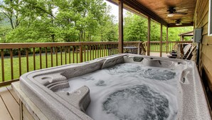 Un jacuzzi en una terraza de madera con vistas a un área verde y árboles.