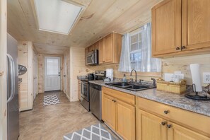 A compact kitchen with wooden cabinets, a microwave, a dishwasher, and a sink.