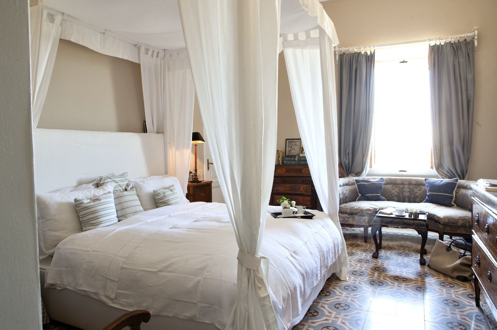 Une chambre à coucher avec un lit à baldaquin, un canapé, une petite table et une table de chevet.