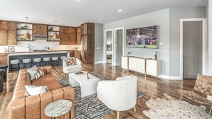 A modern living room with a sofa, coffee table, and TV. - Rooftop Skyline Views DT Nash Sleeps 12 (Nashville)