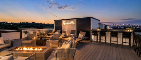 Una terraza en la azotea con asientos al aire libre, una chimenea y un letrero de neón que dice 'Nashville'.