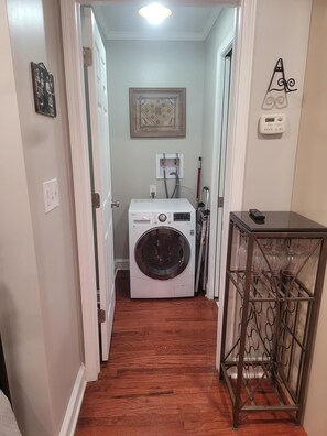 Laundry room with a front-loading washing machine and wine glass storage.