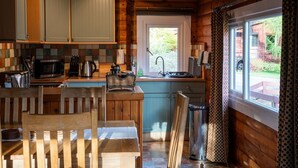 Een houten keuken in chaletstijl met een eethoek, een spoelbak en een raam met uitzicht op een tuin.