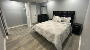 Une chambre à coucher avec un lit, une commode, un miroir et un ventilateur de plafond.