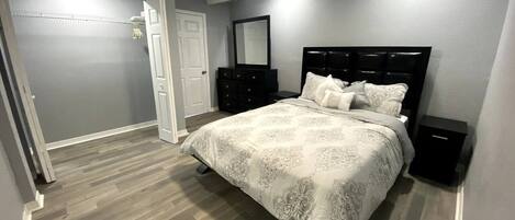 A bedroom with a bed, a ceiling fan, a dresser, and a nightstand.