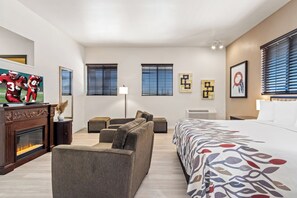 Een hotelkamer met een groot bed, een slaapbank, een open haard en een televisie.