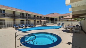 A hotel pool area with lounge chairs, a small pool, and a table with umbrellas. - Red Roof Inn Ridgecrest (Ridgecrest)
