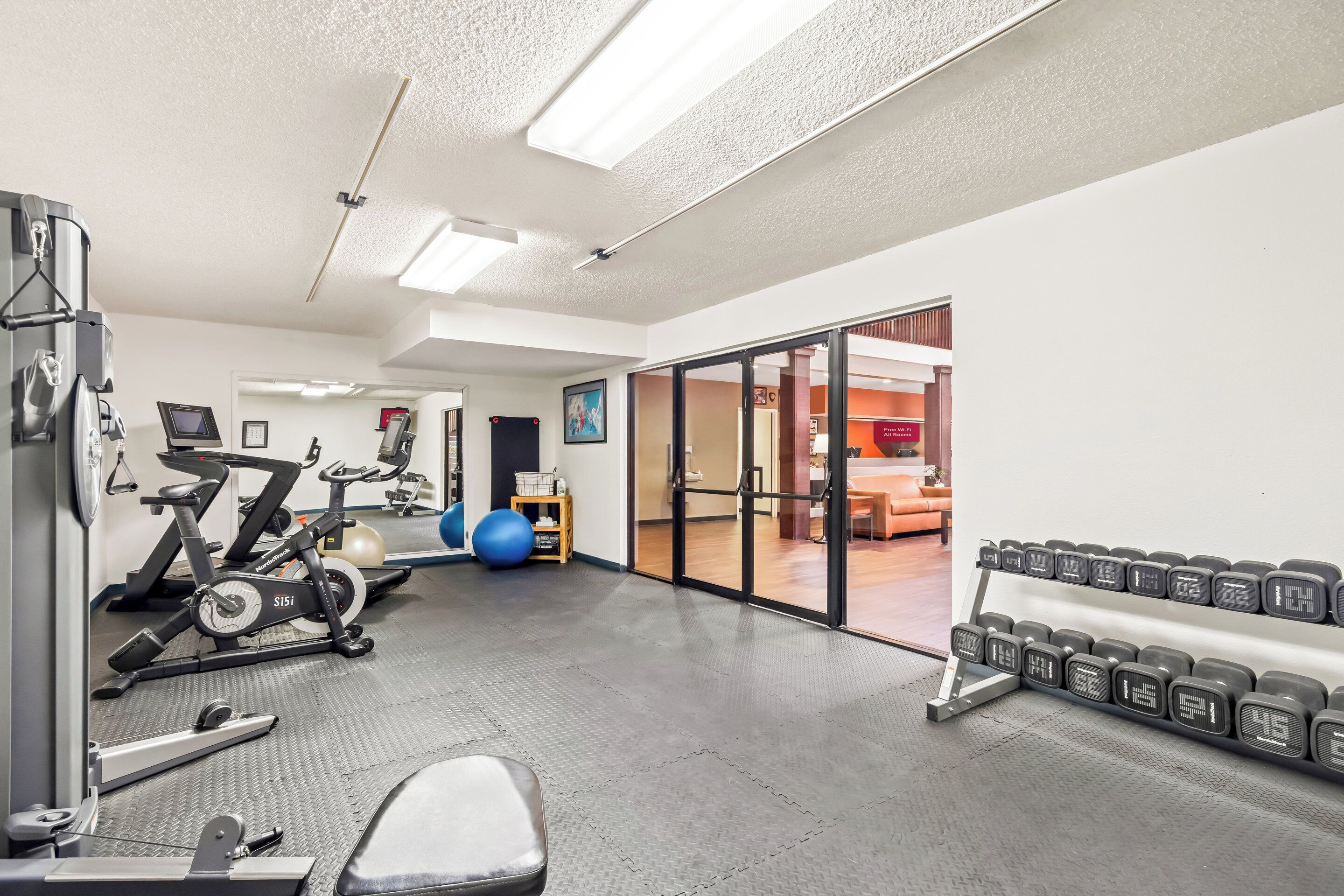Une salle de sport équipée de matériel d’exercice, d’un banc de musculation et d’une horloge numérique.
