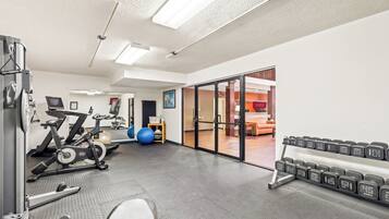 Une salle de sport équipée de matériel d’exercice, d’un banc de musculation et d’une horloge numérique.